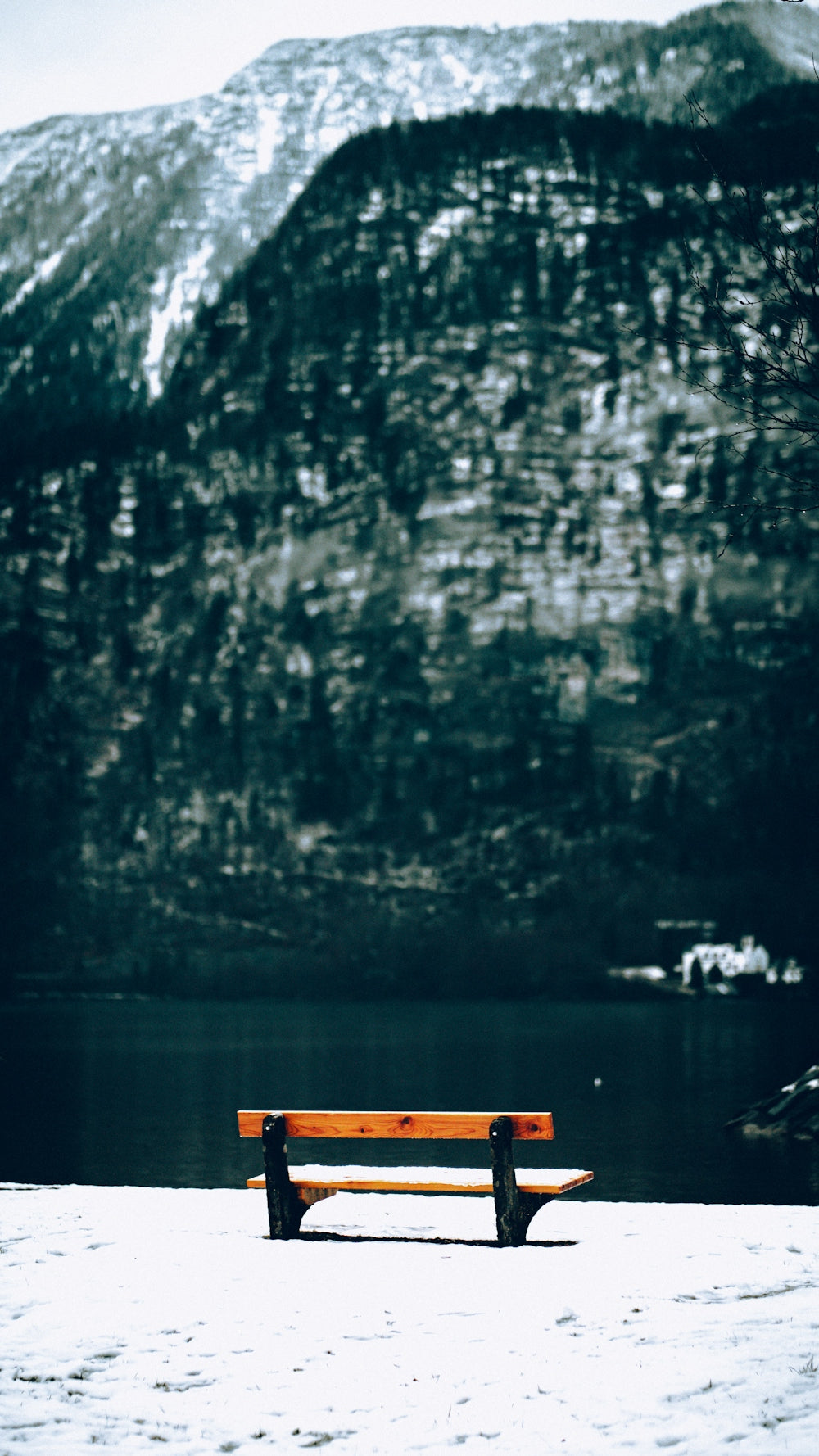 A wooden bench sitting on top of a snow covered ground