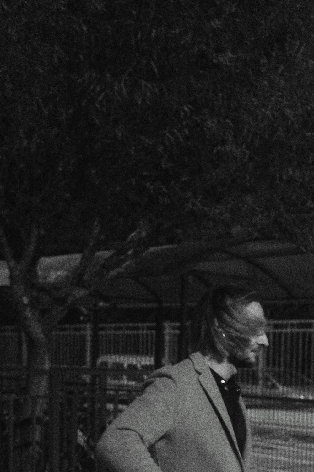Un homme passe devant un arbre en soufflant dans ses cheveux.