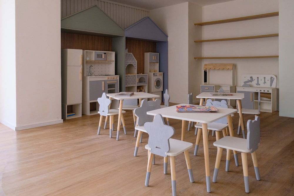 Sala giochi per bambini con tavolini e sedie.