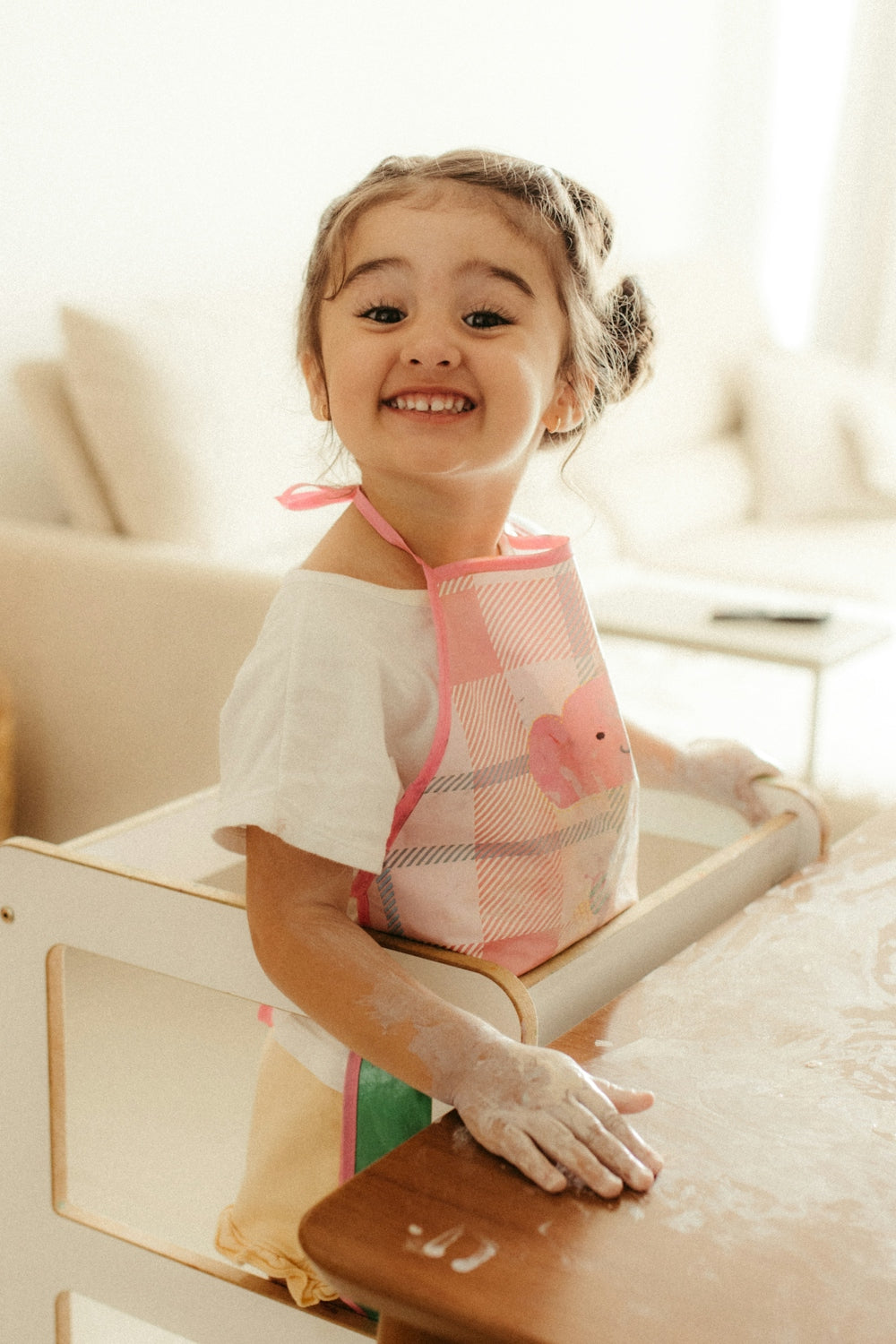 A smiling girl wearing an apron in a kitchen.