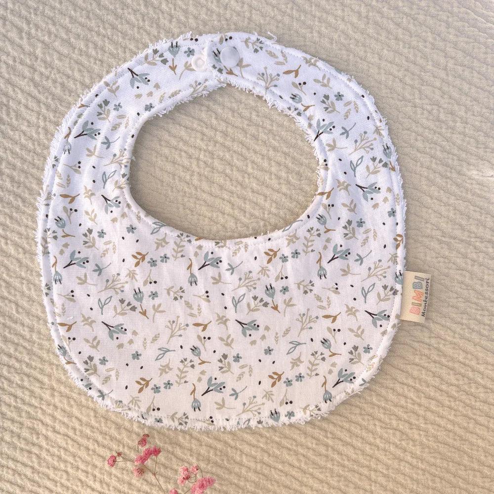 White cotton baby bib with a floral print in green and beige tones, soft and absorbent design by Bimbi Montessori