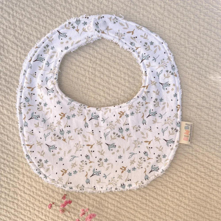 White cotton baby bib with a floral print in green and beige tones, soft and absorbent design by Bimbi Montessori