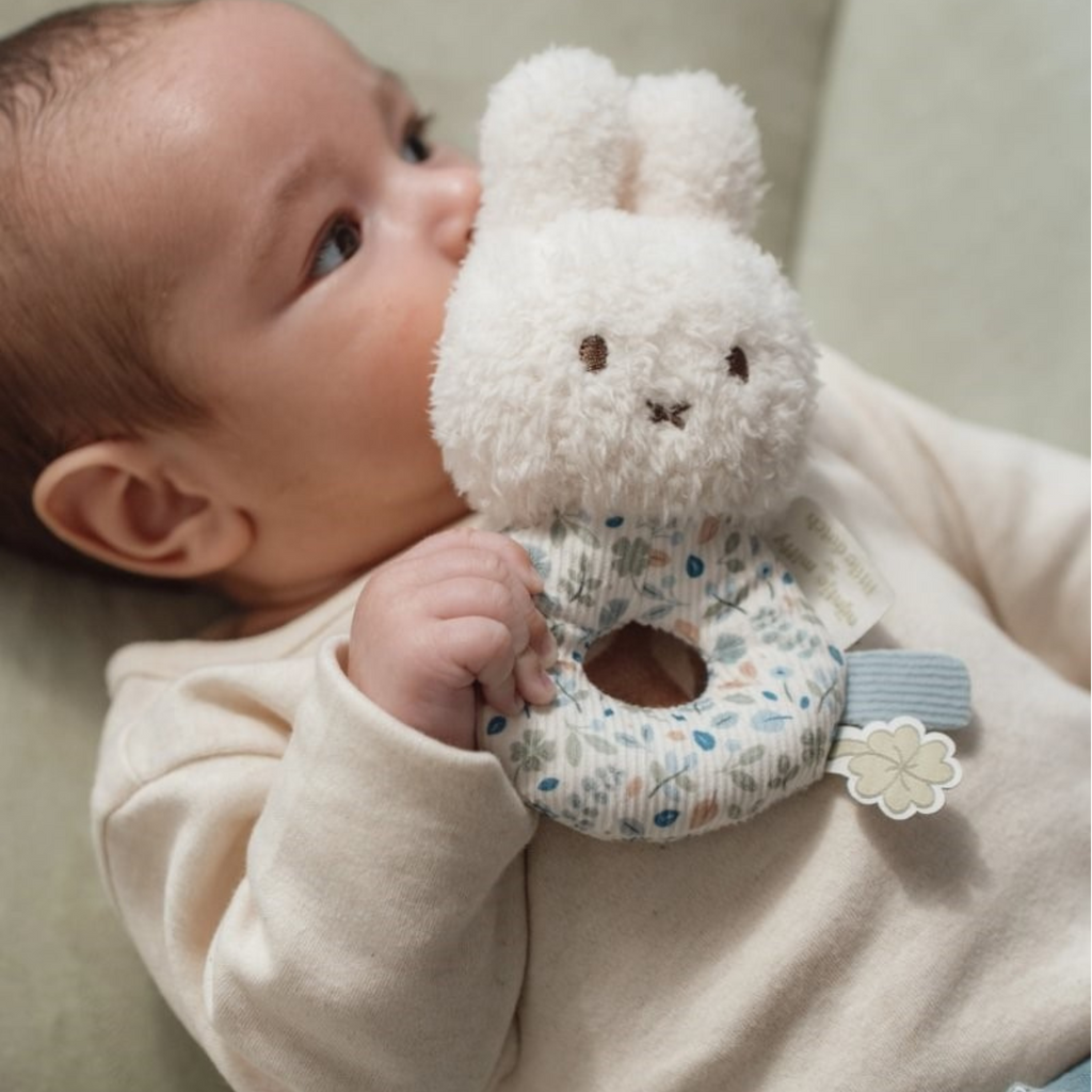 Bebé sujetando sonajero Miffy con aro de tela estampado, ideal para estimular sentidos y agarre