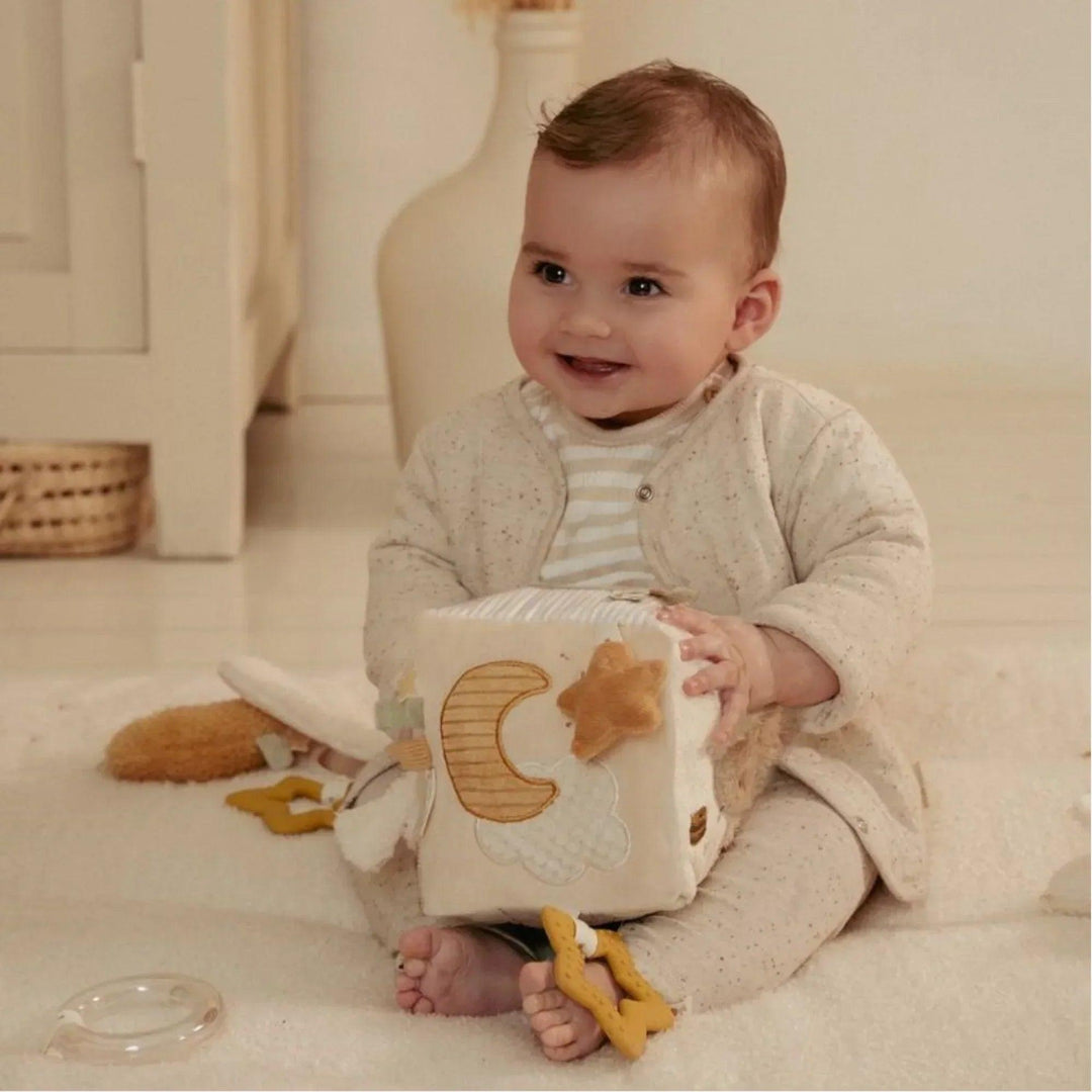 Bébé jouant avec le cube sensoriel Little Dutch dans les tons beige et crème, idéal pour l'exploration tactile.