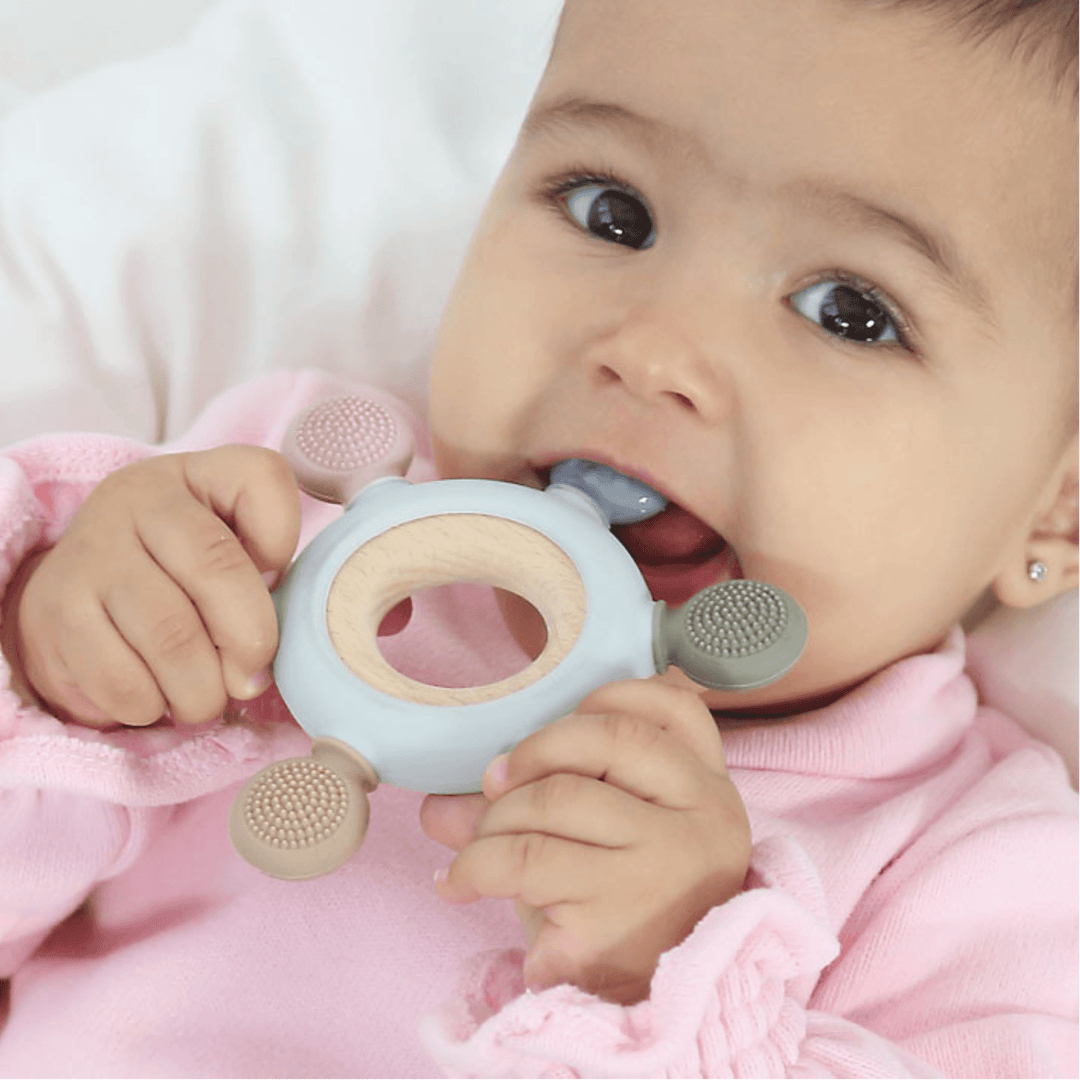 Baby using a wooden and silicone teether. Perfect for soothing gums and encouraging sensory exploration.