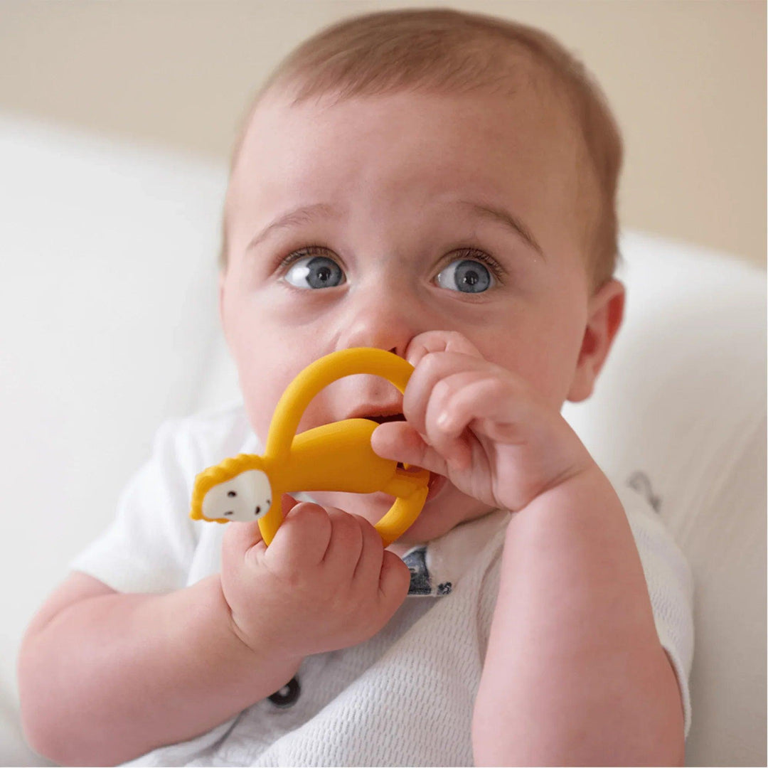 Bébé utilise un anneau de dentition en silicone Matchstick Monkey avec un motif de lion orange pour apaiser ses gencives