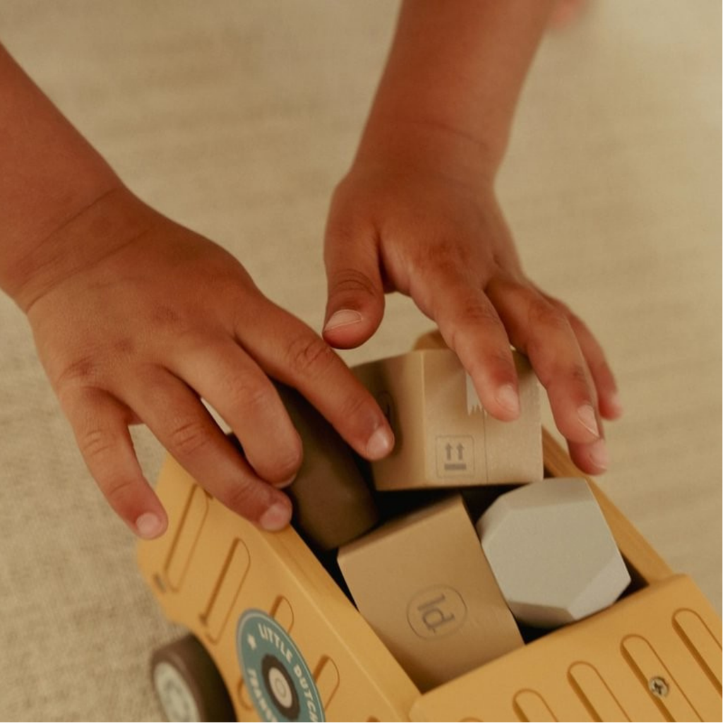 Manos de niño colocando bloques de madera dentro del camión de reparto Little Dutch