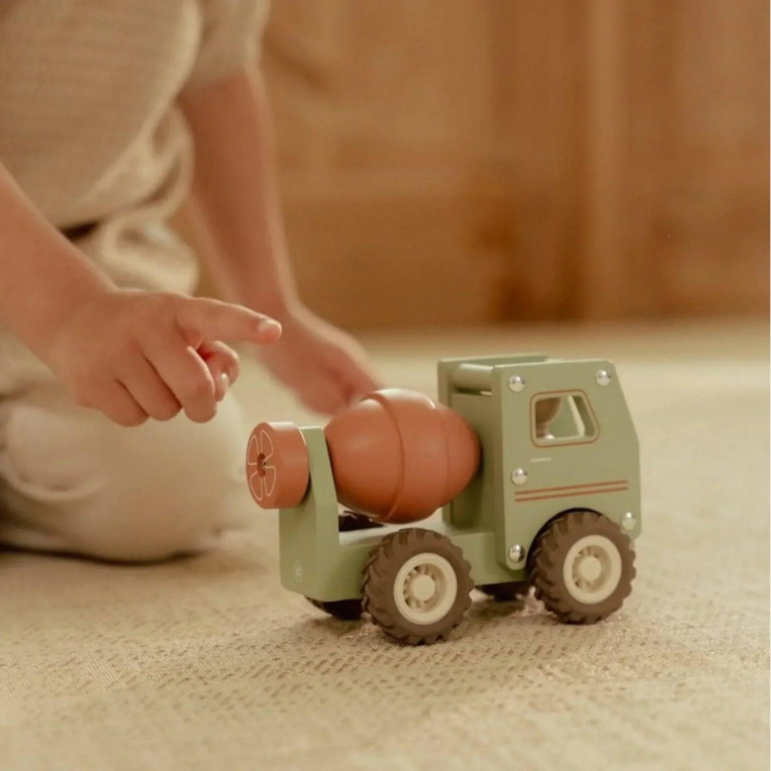 Petit garçon jouant avec le tambour rotatif d'un camion-bétonnière en bois Little Dutch sur un tapis beige.