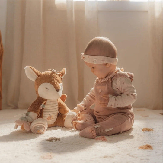 Bébé joue avec une peluche cerf éducative conçue pour stimuler les sens