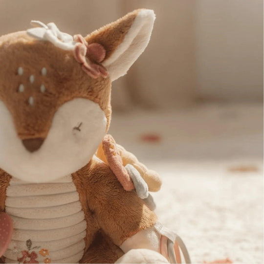 Détail de la peluche de cerf montrant l'oreille avec une fleur décorative et des anneaux multicolores