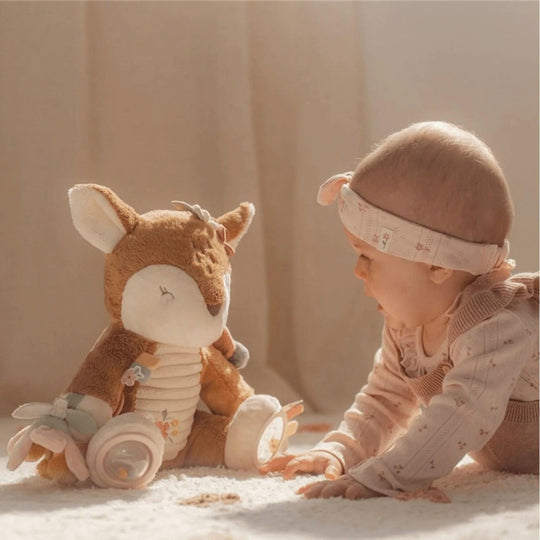 Bébé assis devant une peluche cerf interactive avec accessoires de stimulation sensorielle