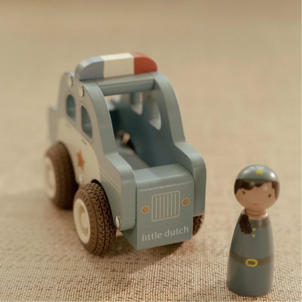Coche de policía de madera color azul con figura de agente Little Dutch sobre una superficie beige