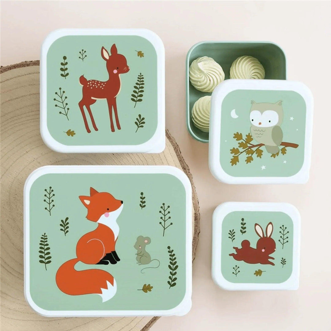 Colección infantil con cajas, cantimplora, estuche y mochila de animales del bosque sobre fondo verde oscuro.