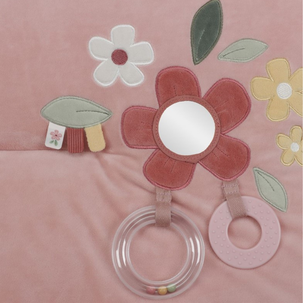 Détail d&#39;une fleur en tissu avec miroir, anneau de dentition et feuilles brodés sur un tapis pour bébé