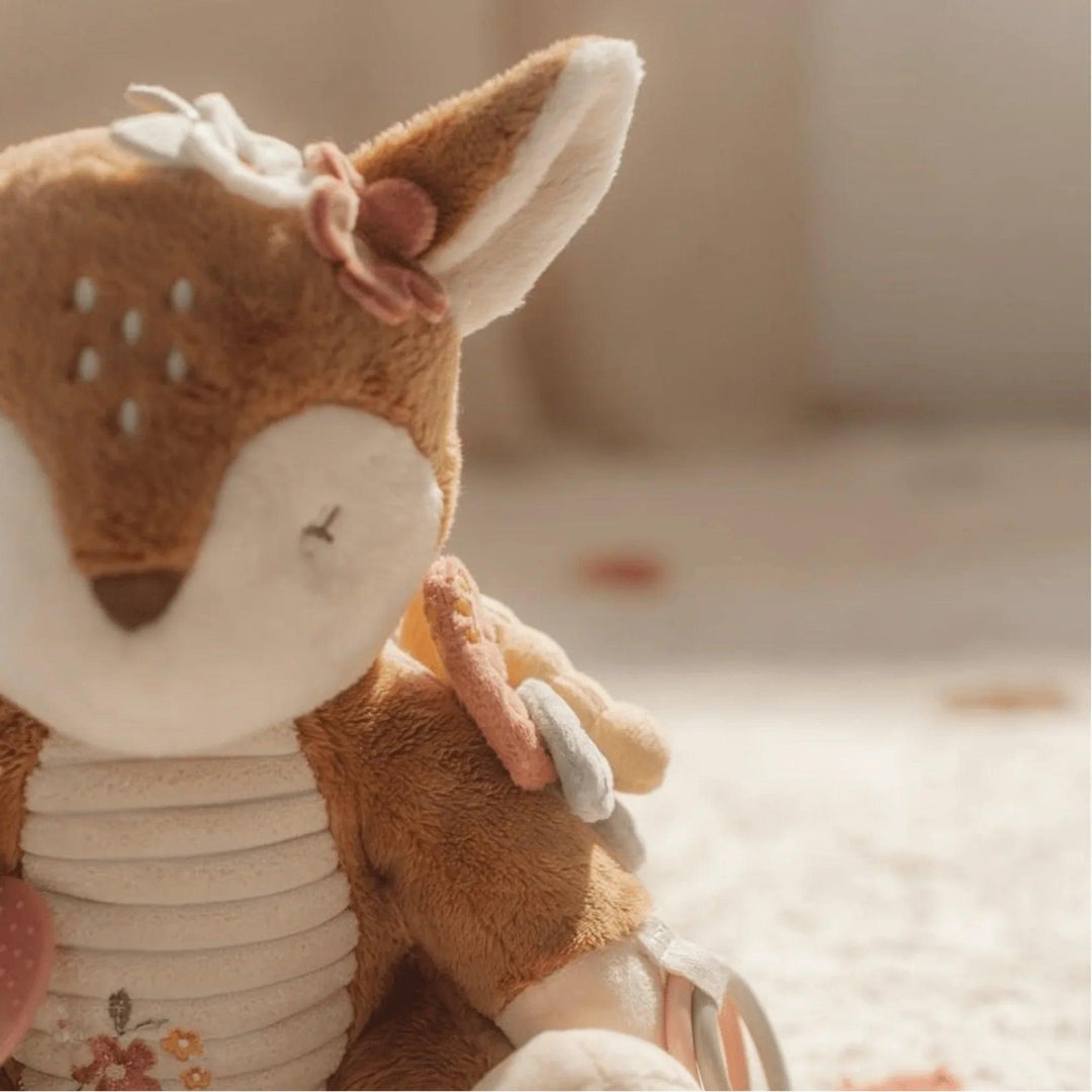 Détail de la peluche de cerf montrant l'oreille avec une fleur décorative et des anneaux multicolores