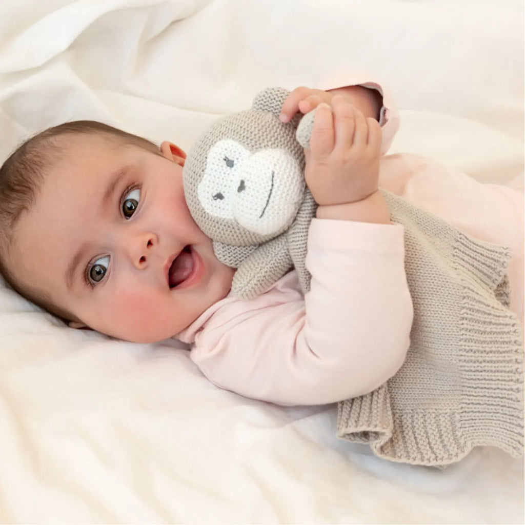Baby hugging a knitted monkey comforter in beige, a soft security blanket for newborns