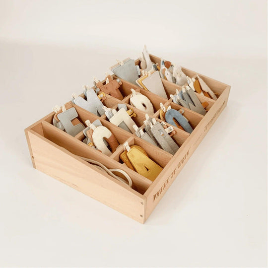 Educational game with soft fabric letters organized in wooden compartments, promoting sensory learning