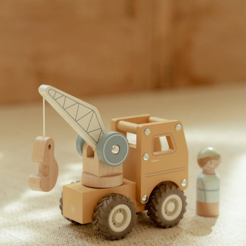 Grúa de madera de juguete Little Dutch con gancho móvil y figura de trabajador junto al vehículo.