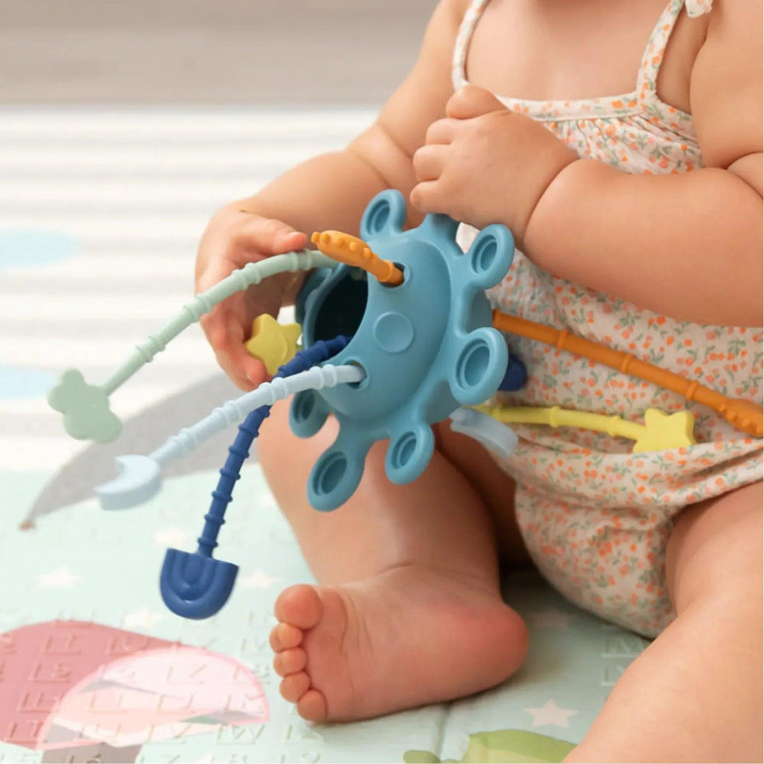 Bebé jugando con un juguete sensorial de silicona con varillas texturizadas.