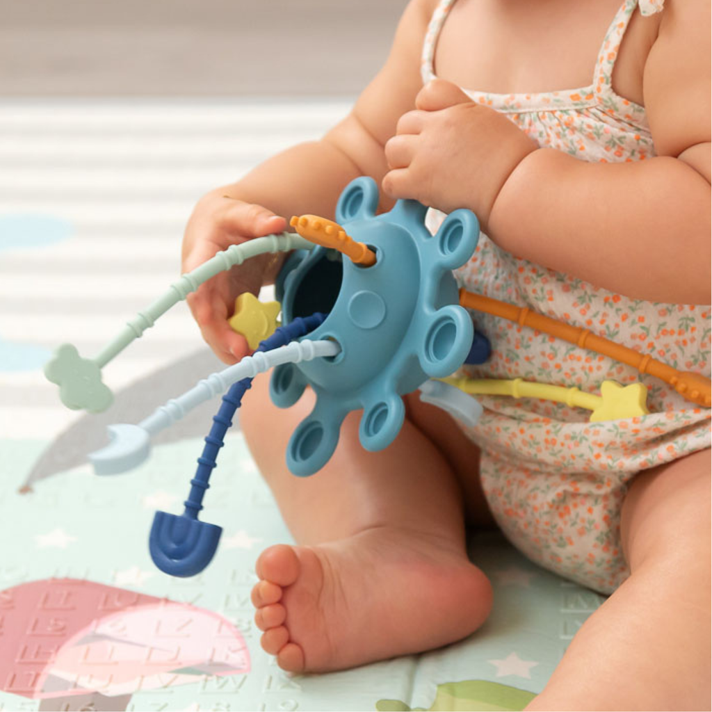 Bebé jugando con un juguete sensorial de silicona con varillas texturizadas.