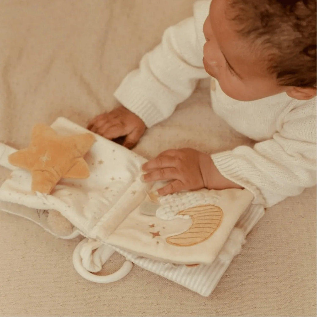 Bébé joue avec un livre en tissu Little Dutch avec lune et étoile dans des tons doux
