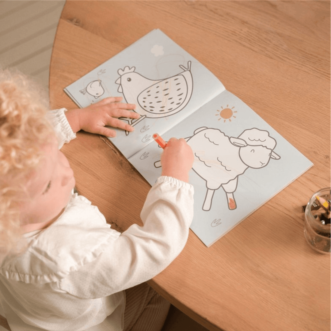 Enfant coloriant des dessins d'animaux de la ferme dans le livre Little Farm de Little Dutch