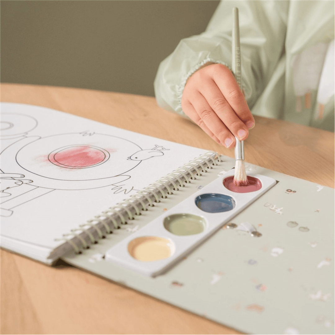 Niño pintando con pincel y acuarelas en el libro infantil Little Dutch Little Farm
