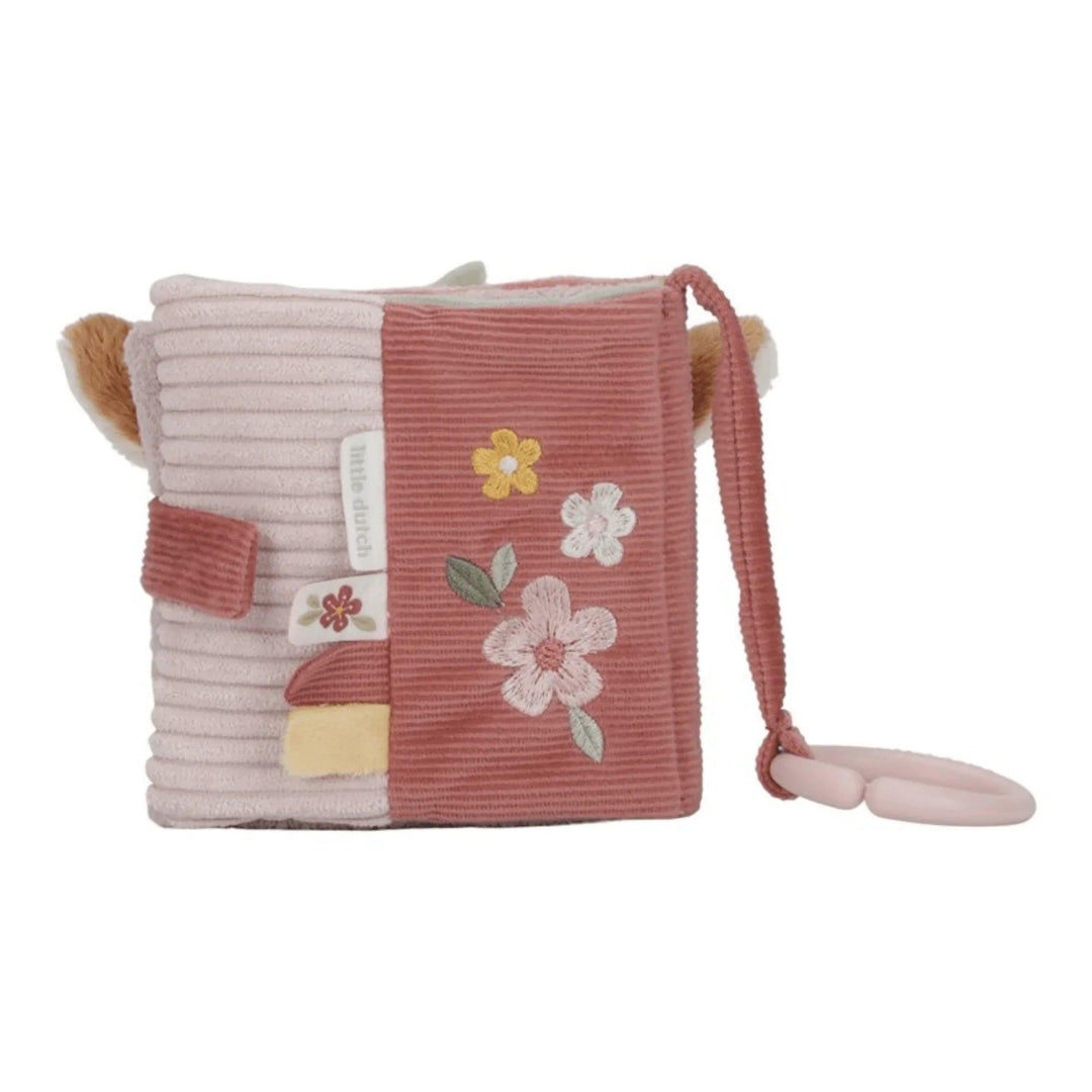 Livre sensoriel en tissu doux pour bébé dans les tons de rose, avec des fleurs brodées et un anneau de suspension.