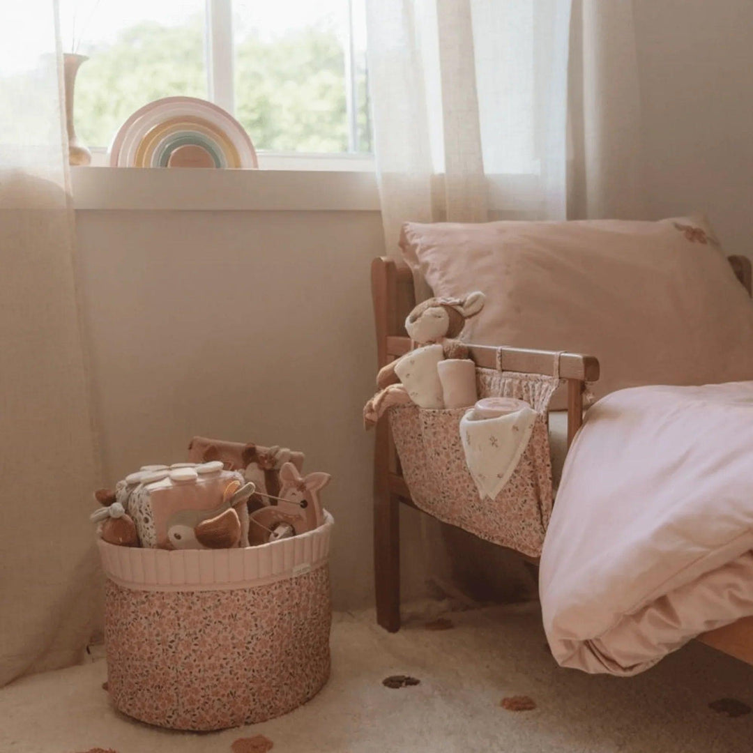 Habitación infantil decorada con canastos de tela Little Dutch color rosa, cama de madera, juguetes y arcoíris decorativo, ambiente acogedor para niñas pequeñas