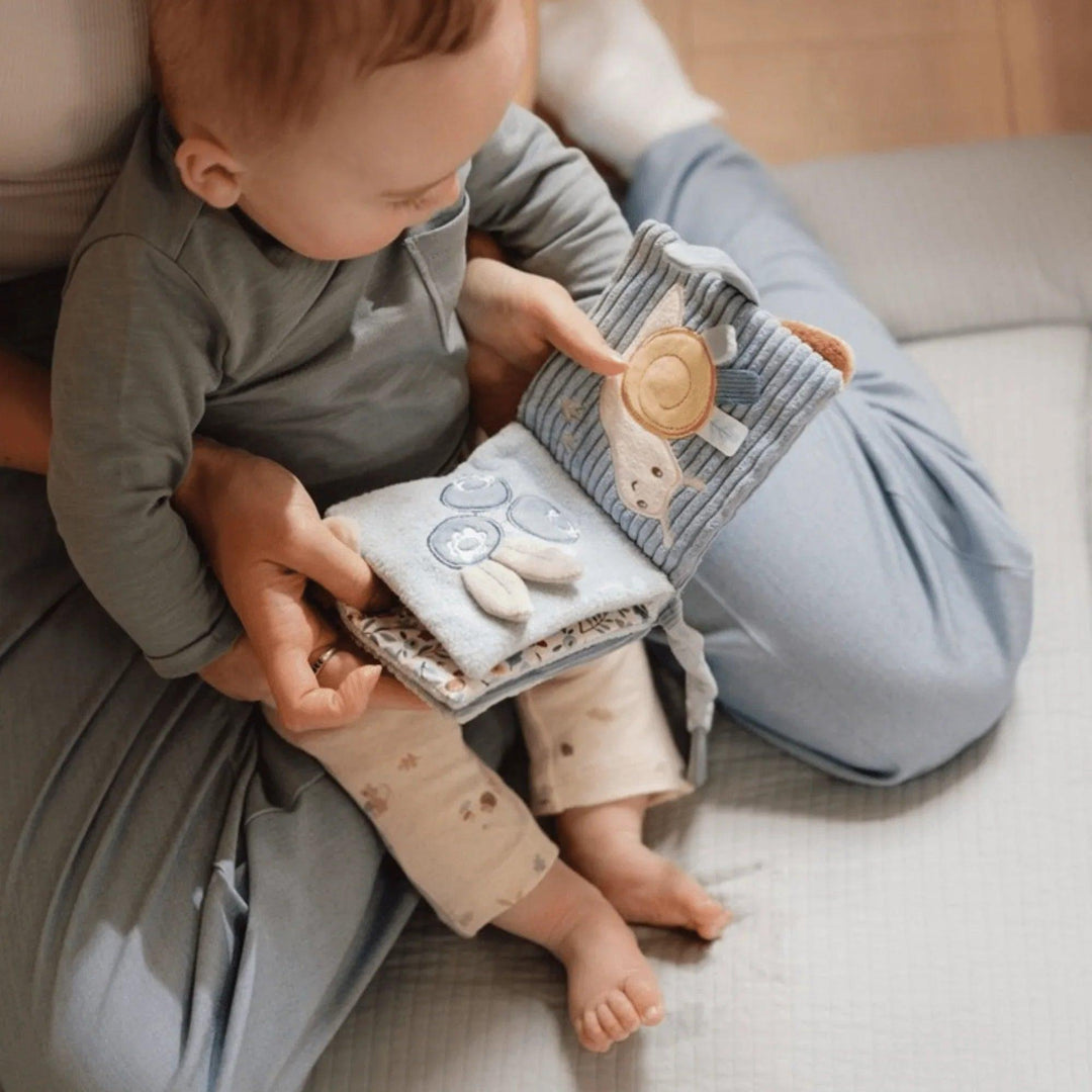 Bambino in braccio che gioca con il libro sensoriale blu Little Dutch, pagine interattive e attività tattili
