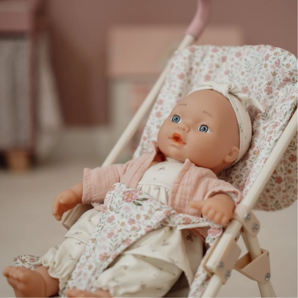 Muñeca bebé Little Dutch con chaqueta rosa y carrito estampado de flores, ambientada en habitación infantil