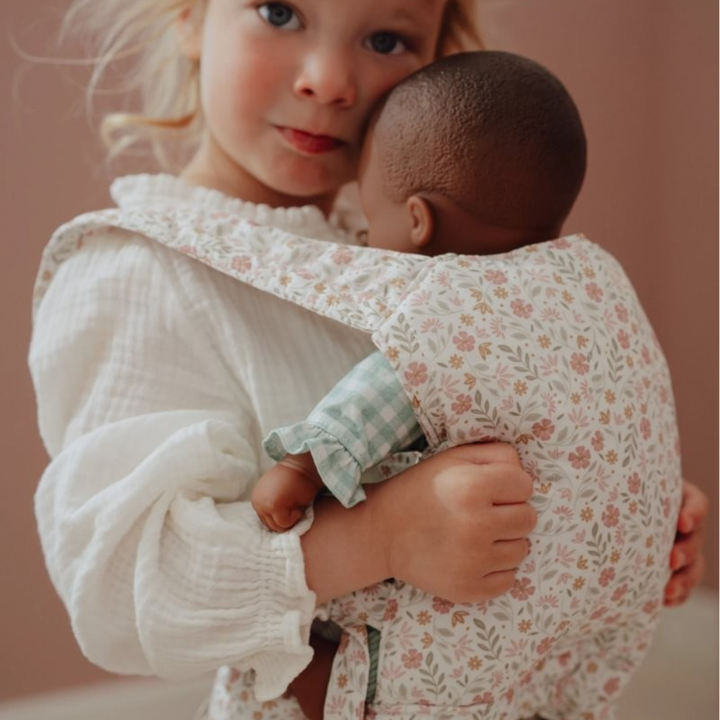 Niña jugando con muñeca usando el portabebés floral Little Dutch, fomentando el juego simbólico y afectivo
