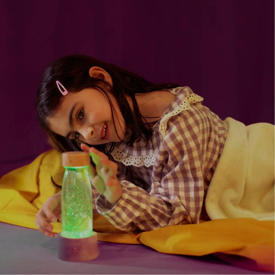 Girl playing with sensory bottle petit boum with green light base for visual stimulation