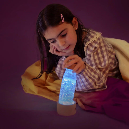 girl observing sensory bottle petit boum with blue light base and glowing effect