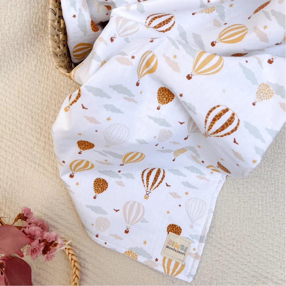 White baby blanket with a hot air balloon print in brown and beige tones