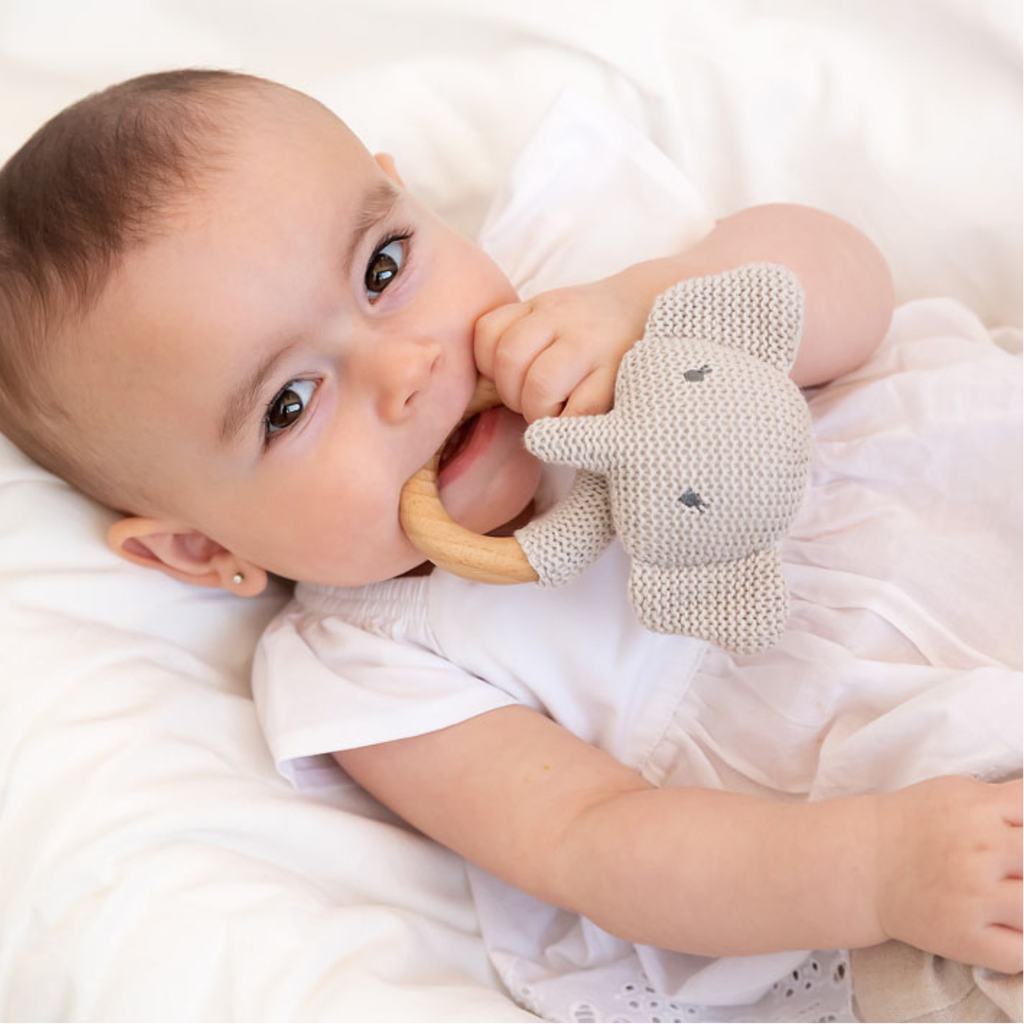 Bebé sosteniendo un mordedor de elefante de crochet con aro de madera natural