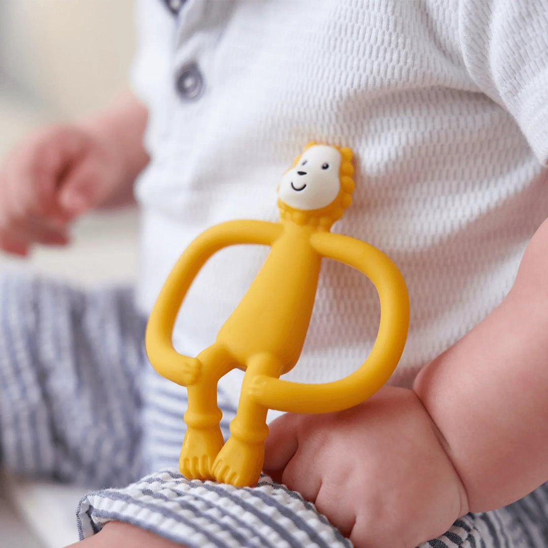 Anneau de dentition lion orange Matchstick Monkey posé sur la main d'un bébé.