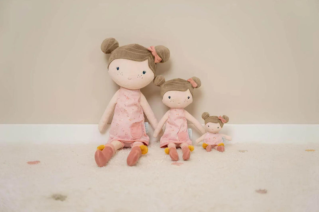 Little Dutch dolls in different sizes, dressed in pink flower dresses and bows in their hair