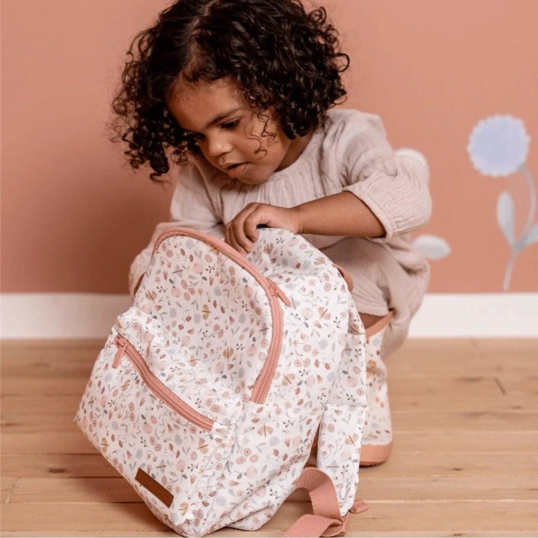Petite fille ouvrant un sac à dos d'école pour enfants à fleurs roses