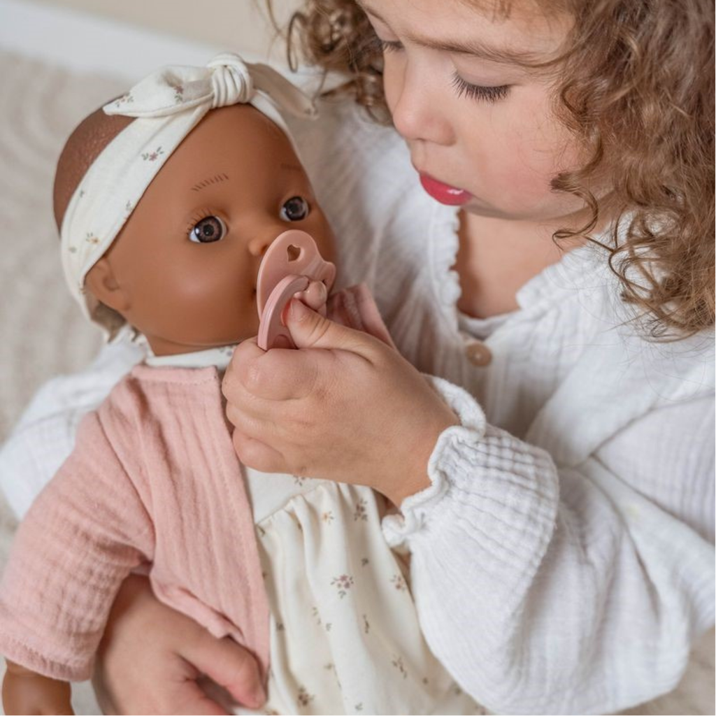 Niña jugando con muñeca bebé Little Dutch con chupete rosa – juguete de imitación ideal para el juego simbólico.