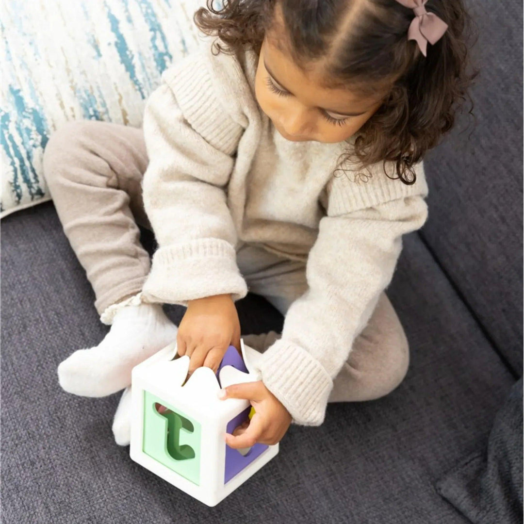 nina jugando con cubo encajable educativo de numeros y formas