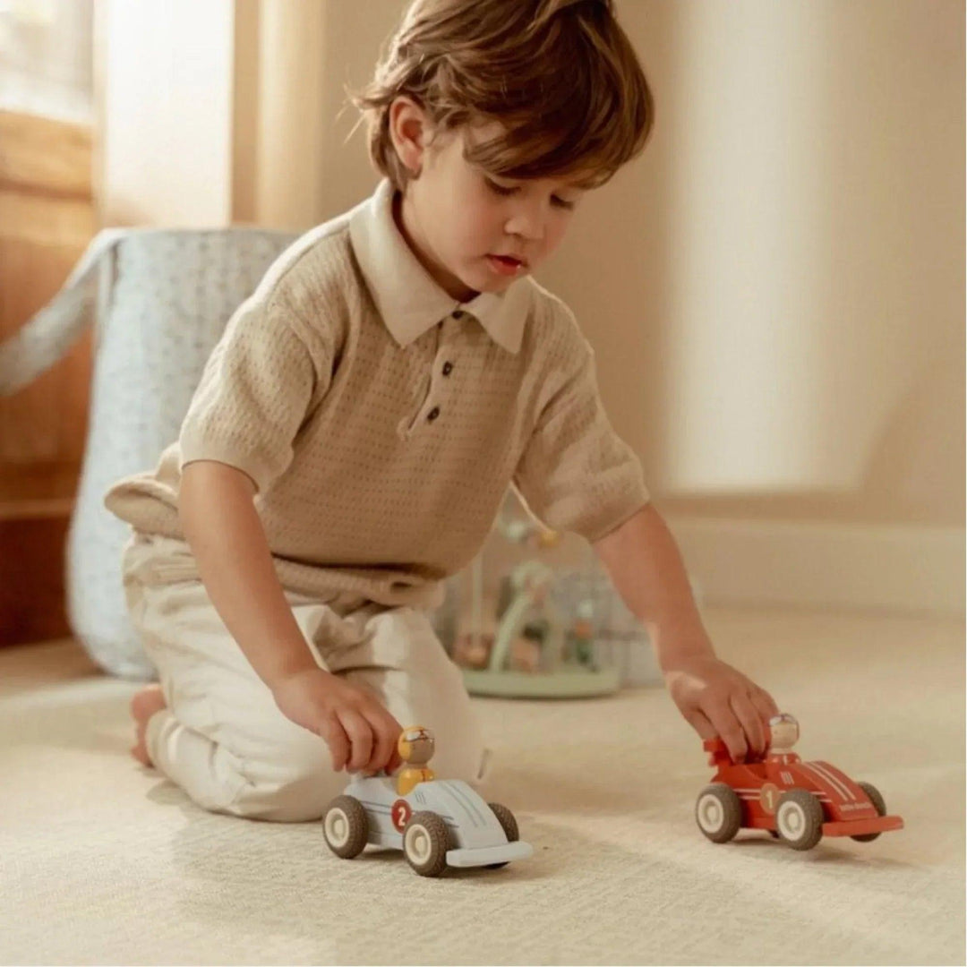 Enfant jouant avec des voitures de course en bois Little Dutch, idéales pour le jeu libre et créatif.