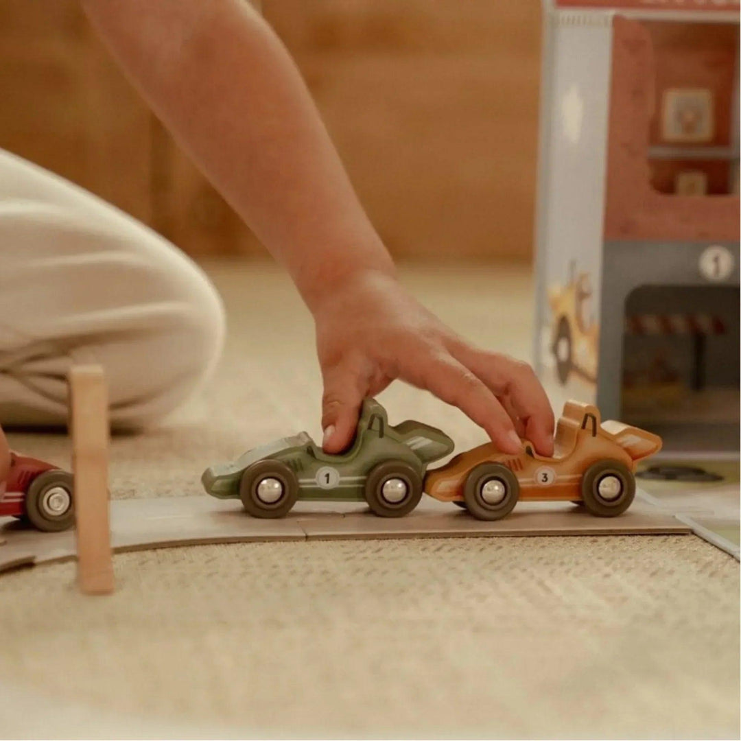 Enfant jouant avec des voitures en bois du circuit de course Little Dutch, encourageant la coordination et l'imagination.