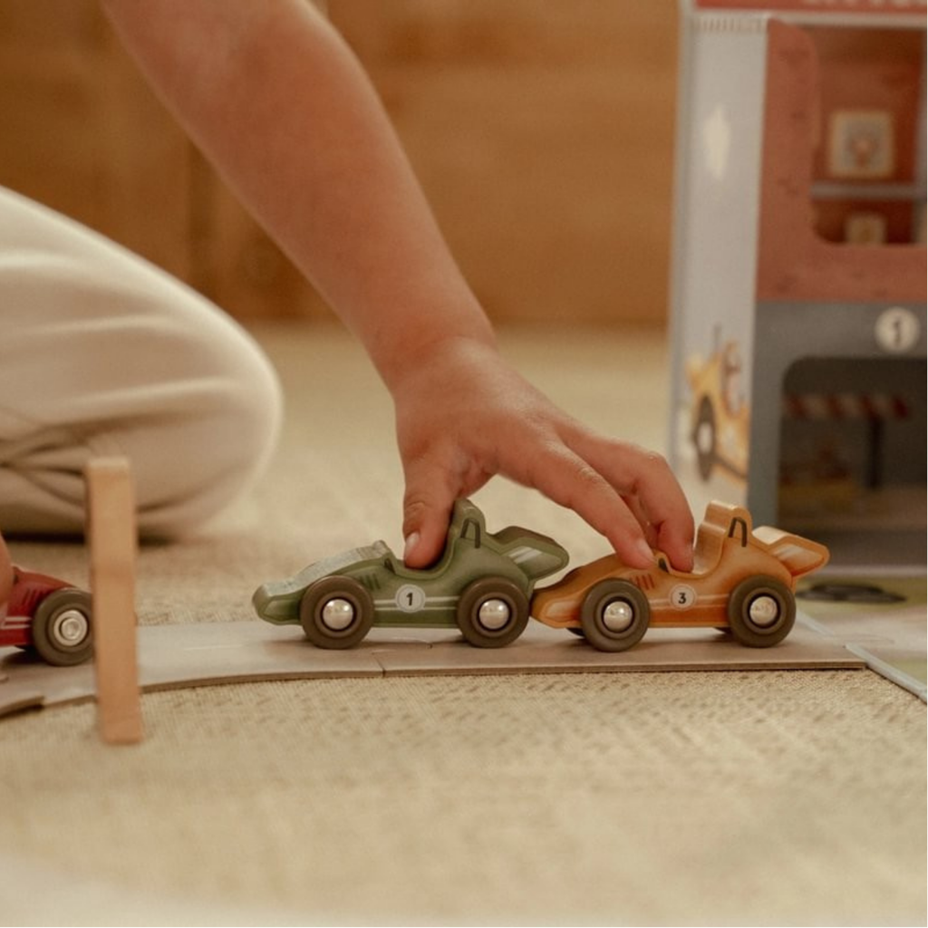 Niño jugando con coches de madera del circuito de carreras Little Dutch, fomentando la coordinación y la imaginación.
