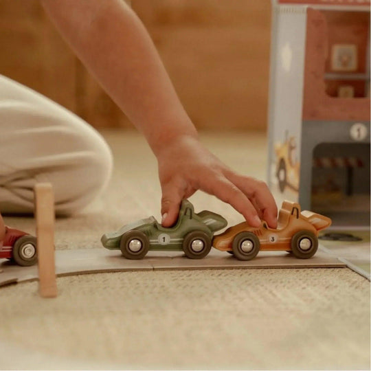 Bambino che gioca con le macchinine di legno della pista da corsa Little Dutch, stimolando la coordinazione e l'immaginazione.