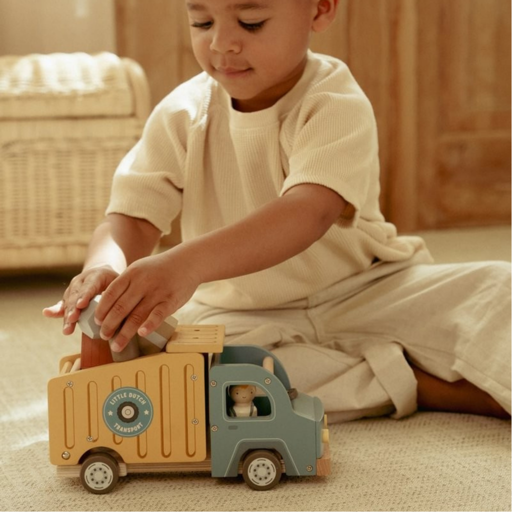Niño jugando con camión de reparto de madera Little Dutch, colocando bloques dentro del compartimento