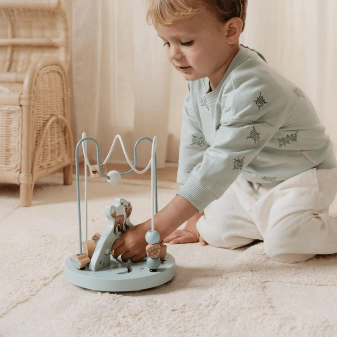 Un tout-petit joue avec un jouet de motricité fine Montessori et des animaux dans une chambre confortable