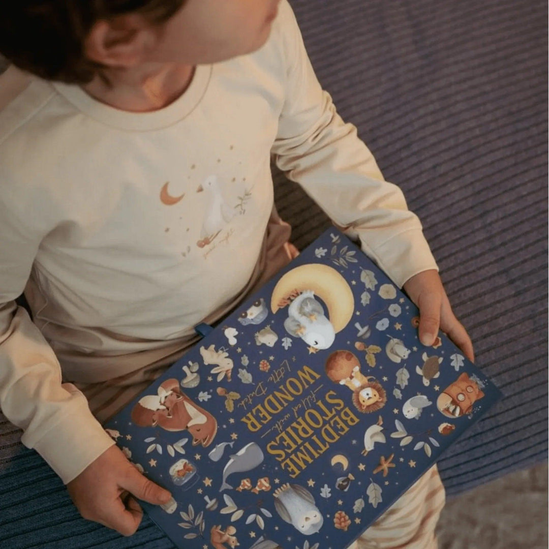 Garçon tenant une boîte d'histoires projetées Little Dutch portant un pyjama beige
