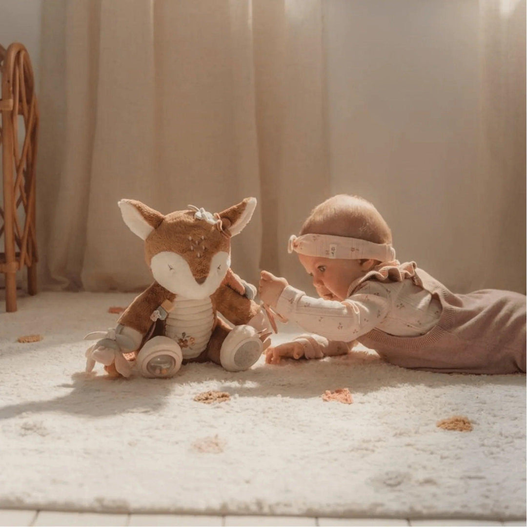 Bébé rampe et touche le cerf en peluche sensorielle avec des textures, des couleurs douces et des éléments suspendus