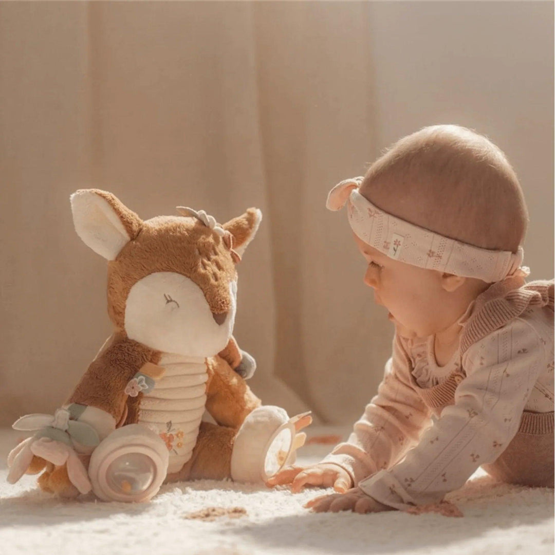 Bébé assis devant une peluche cerf interactive avec accessoires de stimulation sensorielle